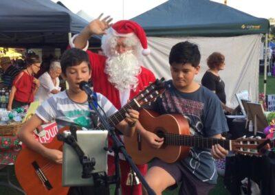 Two young musicians playing guitar with Santa